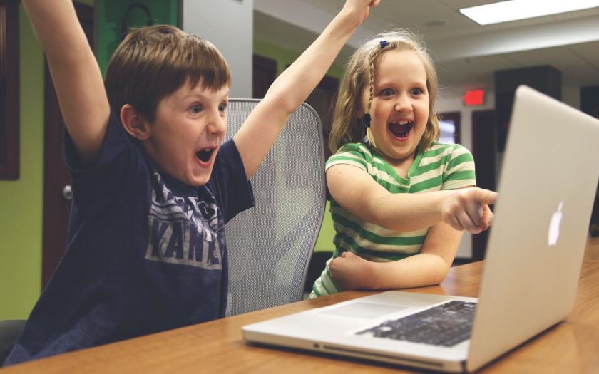 Bild von Kindern vor einem Laptop, die sich sehr freuen und erstaunt auf den Bildschirm blicken.